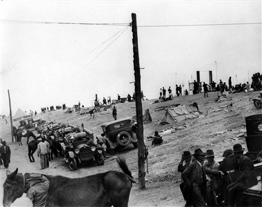 People, animals, and equipment on a levee surrounded by water